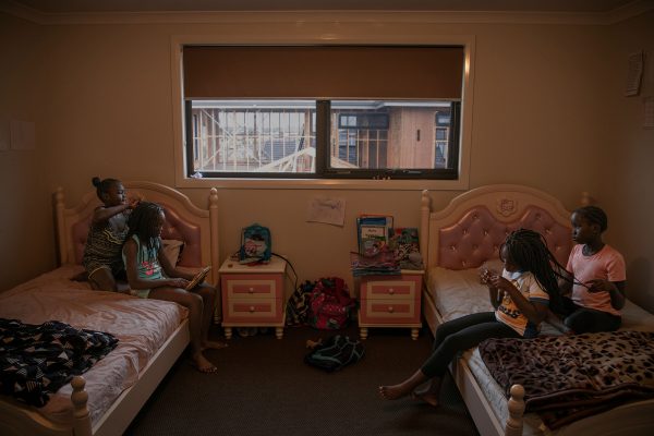 In a quiet moment, cousins and siblings braid each others’ hair in one of the girls’ rooms at their new home in Cranbourne, a suburb on the outskirts of Melbourne. Their parents prepare food downstairs for the upcoming house blessing ceremony.