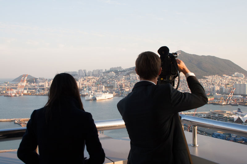 Two journalists look out with a camera in Busan, Korea